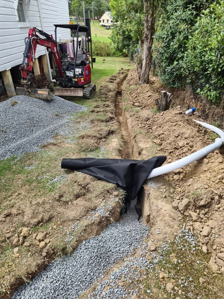 Trench pulled through a soggy backyard for an ag drain, slotted pipe ready to bed in.